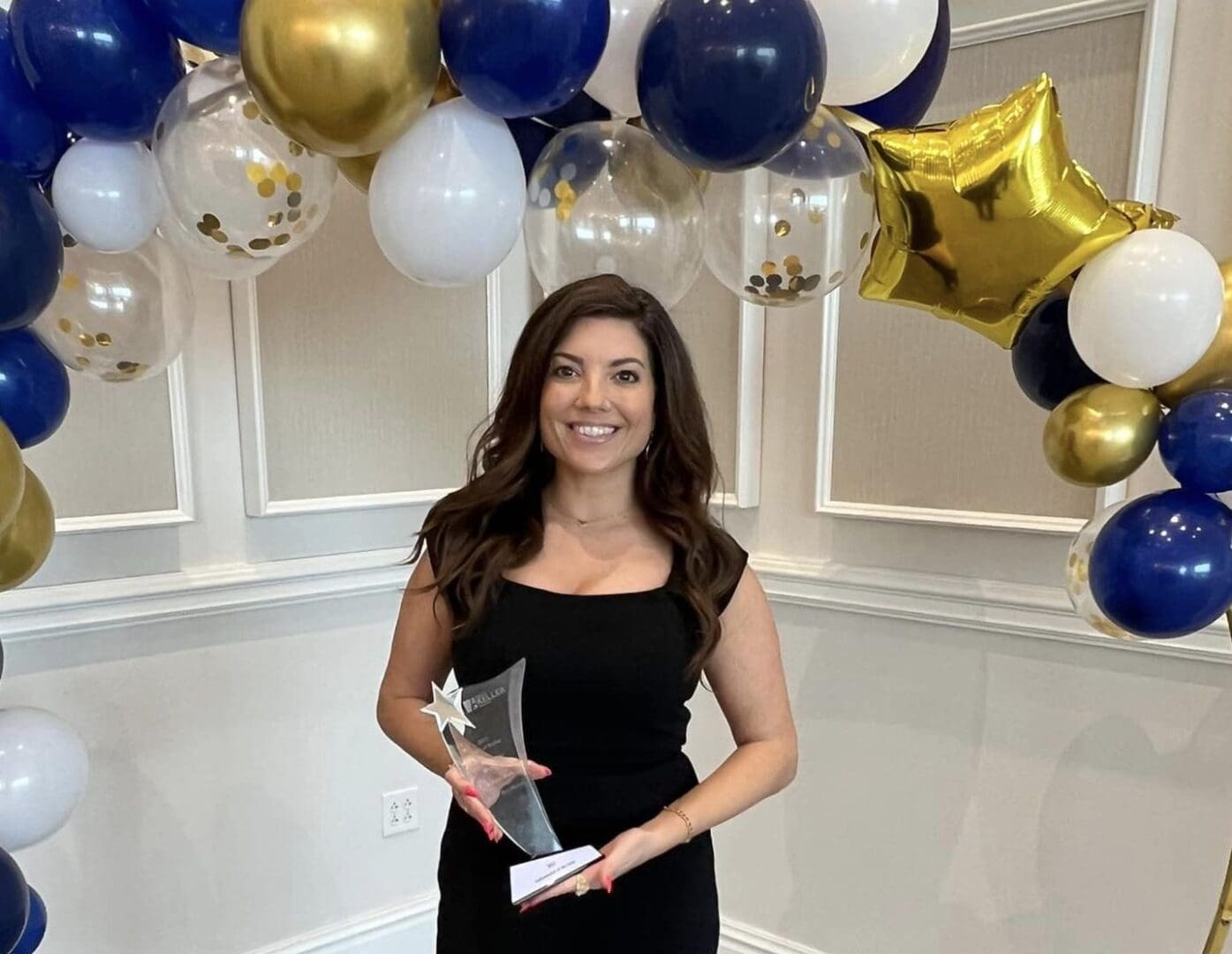 A woman holding an award in front of balloons.