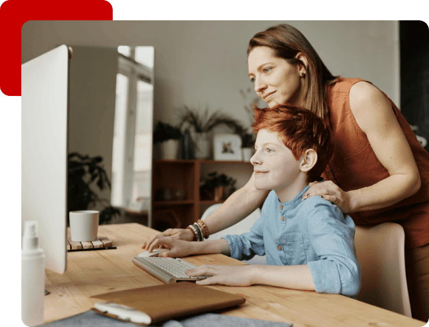 A woman and boy sitting at a table with a computer.